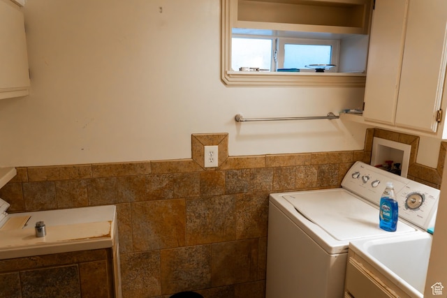 washroom with sink, tile walls, and separate washer and dryer