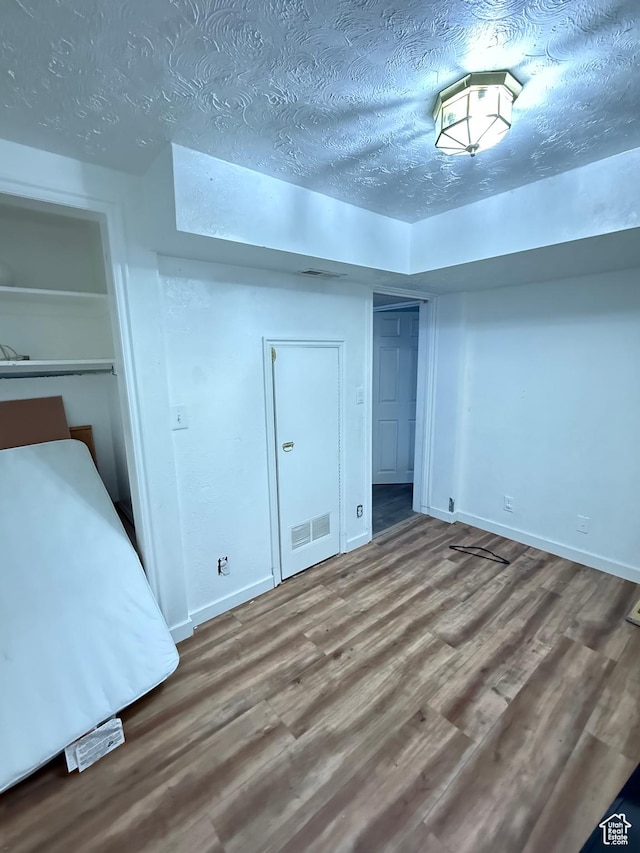 unfurnished bedroom with wood-type flooring and a textured ceiling
