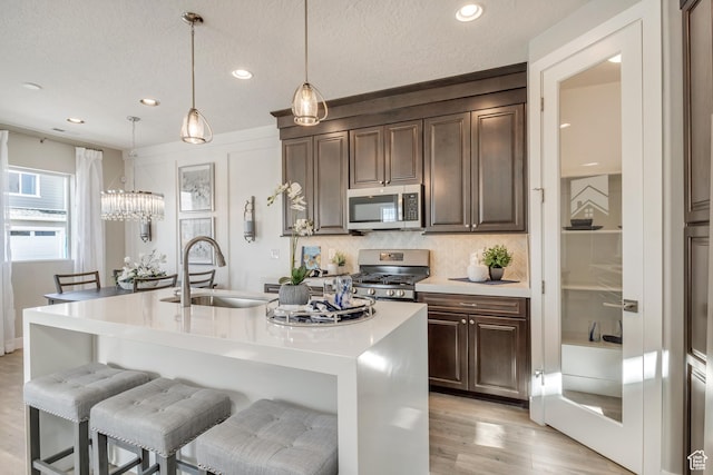 3791 S 3235 W Unit 15, West Haven, UT 84401 - kitchen with sink, decorative light fixtures, stainless steel appliances, a kitchen island with sink, and decorative backsplash