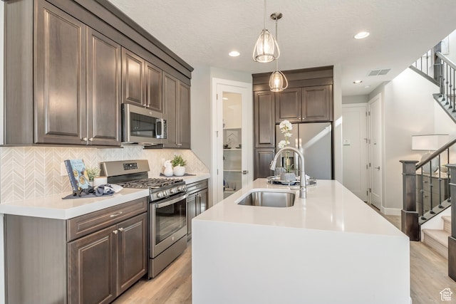 3791 S 3235 W Unit 15, West Haven, UT 84401 - kitchen featuring sink, decorative light fixtures, light hardwood / wood-style floors, stainless steel appliances, and an island with sink