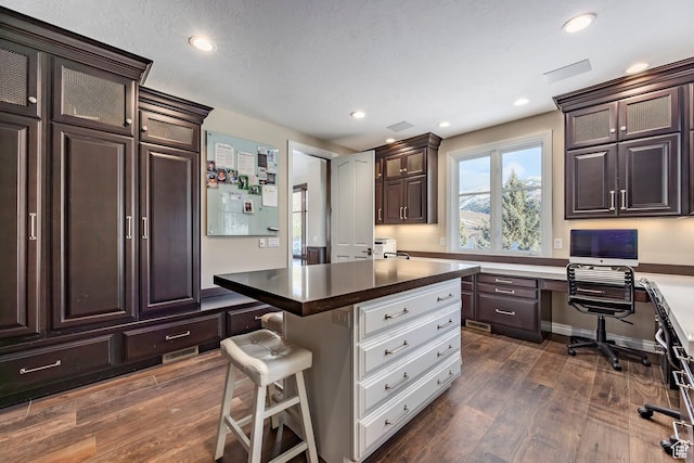 2845 S Wood Hollow Way, Bountiful, UT 84010 - kitchen featuring dark brown cabinetry, dark wood-style flooring, a kitchen breakfast bar, recessed lighting, and glass insert cabinets