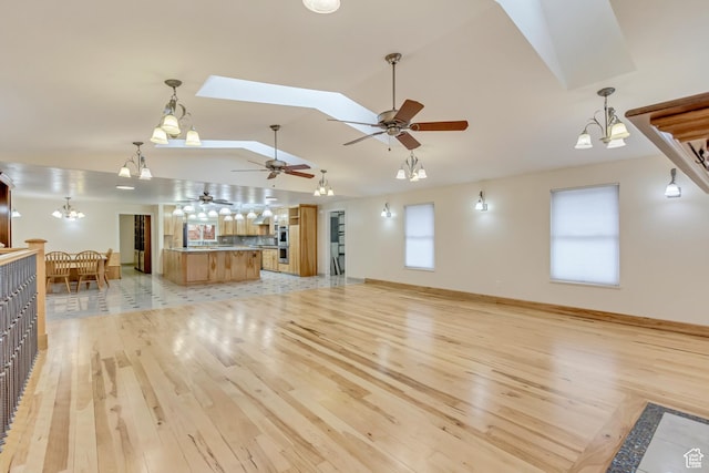 3780 W 5850 S, Roy, UT 84067 - unfurnished living room featuring vaulted ceiling with skylight, an inviting chandelier, and light hardwood / wood-style floors
