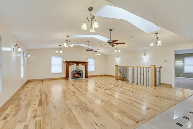 3780 W 5850 S, Roy, UT 84067 - unfurnished living room featuring ceiling fan with notable chandelier, light hardwood / wood-style flooring, and vaulted ceiling with skylight