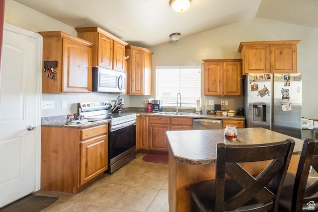 kitchen with appliances with stainless steel finishes, lofted ceiling, light tile patterned flooring, a center island, and sink