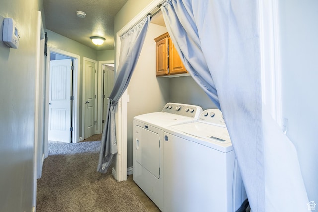 laundry area with washing machine and dryer, a textured ceiling, cabinets, and light colored carpet