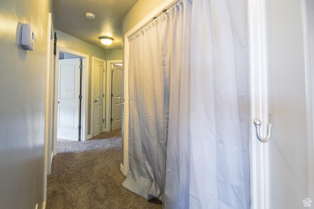 corridor with carpet flooring and a textured ceiling