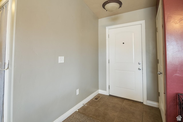 doorway to outside with dark tile patterned flooring