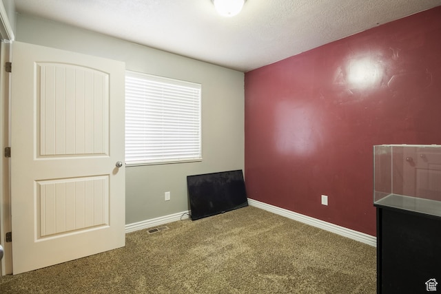 empty room with carpet floors and a textured ceiling