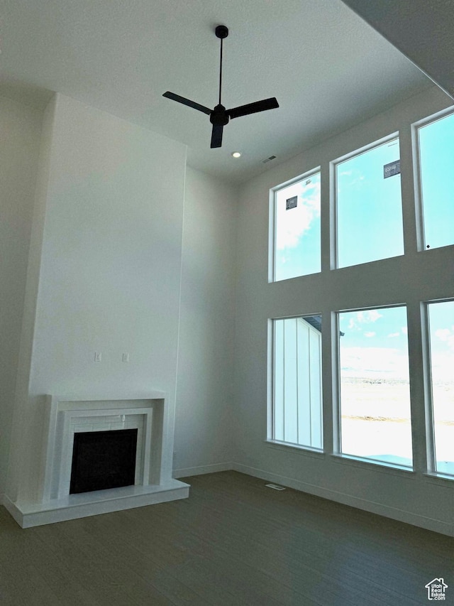 2895 E Liam Ln Unit 106, Eagle Mountain, UT 84005 - unfurnished living room featuring ceiling fan, baseboards, wood finished floors, a fireplace with raised hearth, and a towering ceiling