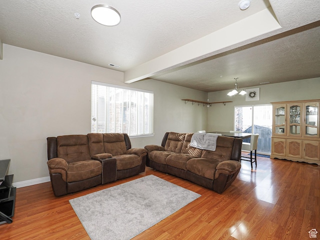 7058 S Greensand Dr, West Jordan, UT 84084 - living room with beam ceiling, a textured ceiling, an inviting chandelier, and wood-type flooring