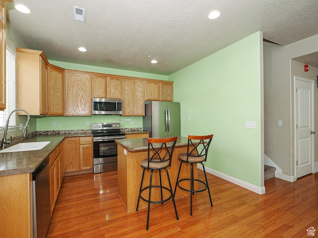 7058 S Greensand Dr, West Jordan, UT 84084 - kitchen featuring a kitchen island, light wood-type flooring, appliances with stainless steel finishes, and sink