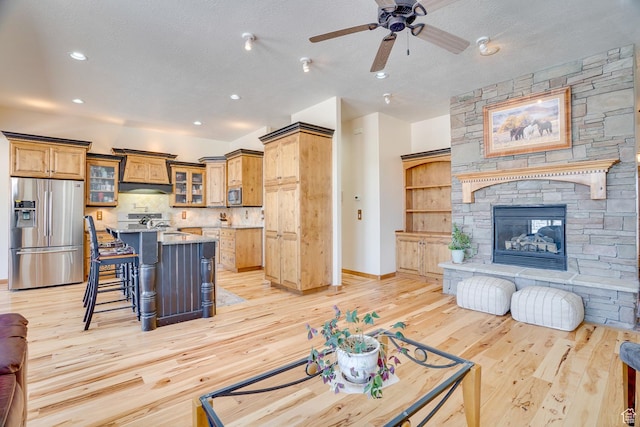 living area with a textured ceiling, recessed lighting, light wood finished floors, and a fireplace