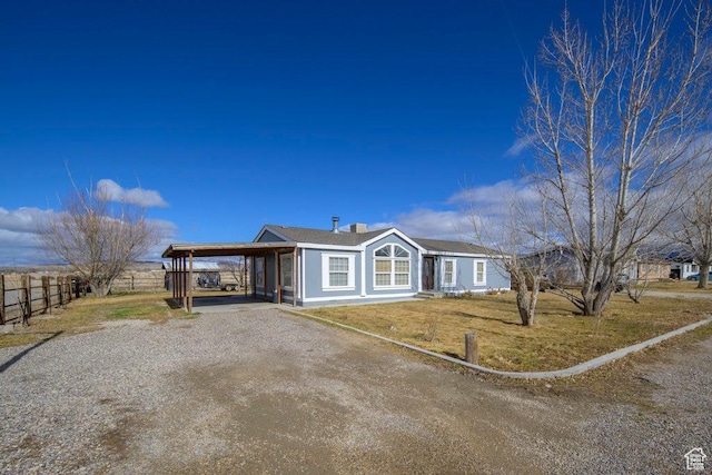 view of front of house featuring gravel driveway, fence, and an attached carport