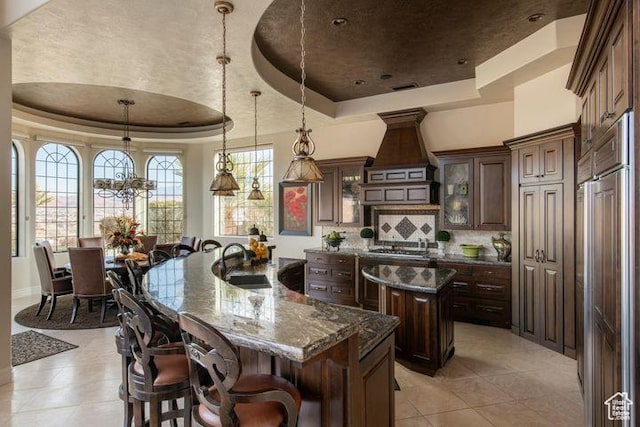2024 W 450th Cir S, St George, UT 84770 - kitchen featuring a sink, a kitchen island with sink, pendant lighting, a raised ceiling, and glass insert cabinets