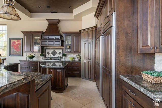 2024 W 450th Cir S, St George, UT 84770 - kitchen with dark stone counters, decorative backsplash, a tray ceiling, dark brown cabinetry, and glass insert cabinets