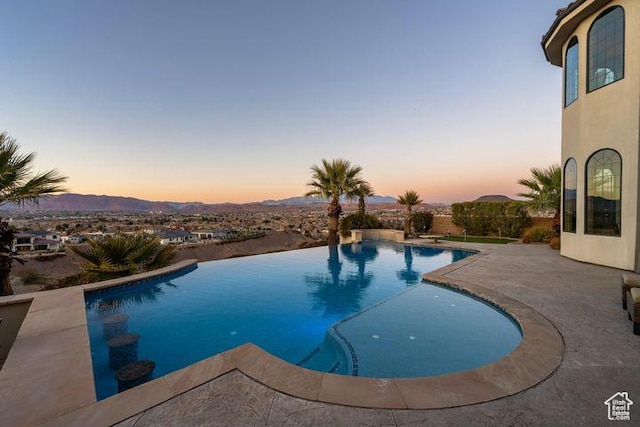2024 W 450th Cir S, St George, UT 84770 - pool at dusk featuring a patio area, an infinity pool, and a mountain view