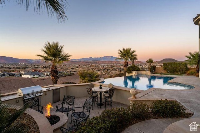 2024 W 450th Cir S, St George, UT 84770 - view of swimming pool with an infinity pool, a fire pit, a mountain view, a patio area, and area for grilling