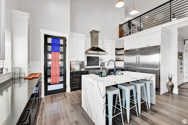 2673 S 4950 W, Taylor, UT 84401 - kitchen with an island with sink, decorative light fixtures, wall chimney range hood, white cabinetry, and open shelves