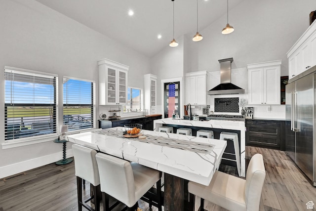 2673 S 4950 W, Taylor, UT 84401 - kitchen featuring built in fridge, a kitchen island with sink, decorative light fixtures, wall chimney range hood, and glass insert cabinets