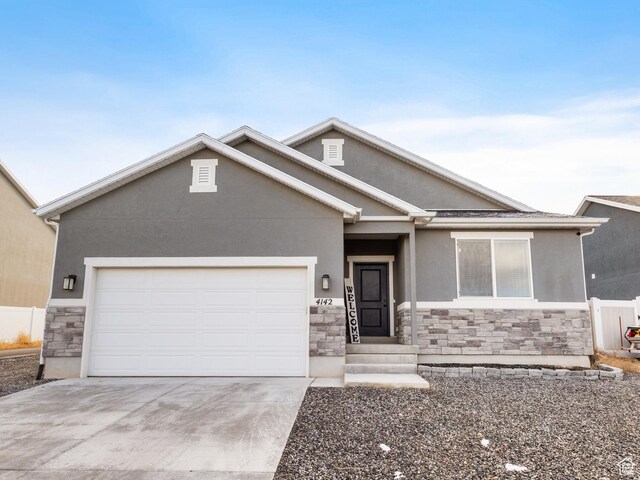 view of front facade featuring stone siding, concrete driveway, an attached garage, and stucco siding