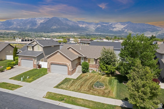 view of front of property featuring fence, brick siding, a mountain view, driveway, and stucco siding