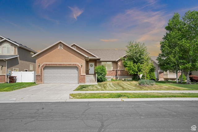 single story home with fence, brick siding, concrete driveway, a garage, and a front yard