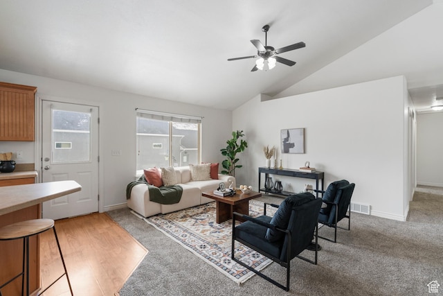 living area with lofted ceiling, visible vents, ceiling fan, and light colored carpet