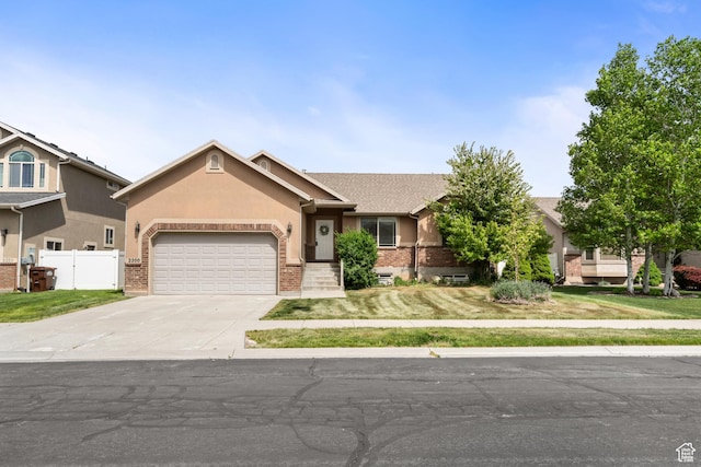 ranch-style home featuring fence, an attached garage, brick siding, concrete driveway, and stucco siding