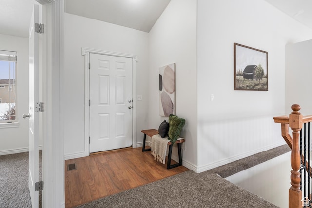 carpeted entryway featuring baseboards, visible vents, and wood finished floors