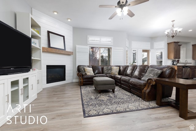 3013 W Alta Peak Rd, South Jordan, UT 84095 - living area featuring light wood-style floors, a wealth of natural light, a fireplace, and ceiling fan with notable chandelier