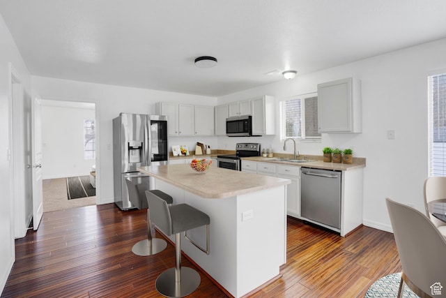 298 Beaumont Dr, Kaysville, UT 84037 - kitchen featuring stainless steel appliances, a sink, a breakfast bar, light countertops, and dark wood-type flooring