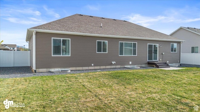 rear view of property with fence, a shingled roof, and a yard