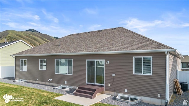 rear view of house featuring roof with shingles, fence, and central air condition unit