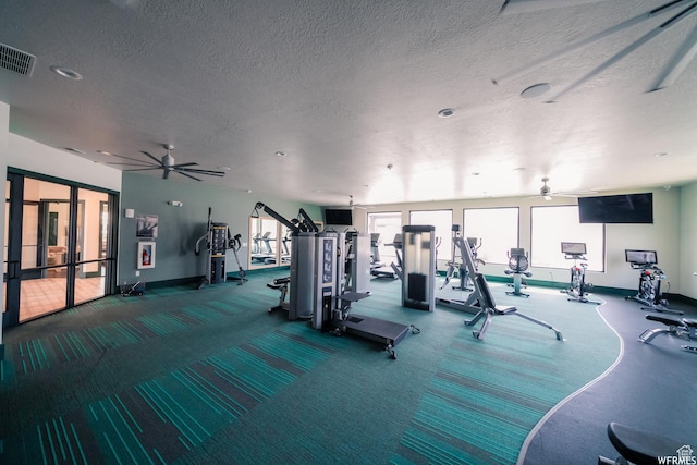 workout area featuring plenty of natural light, ceiling fan, a textured ceiling, visible vents, and baseboards
