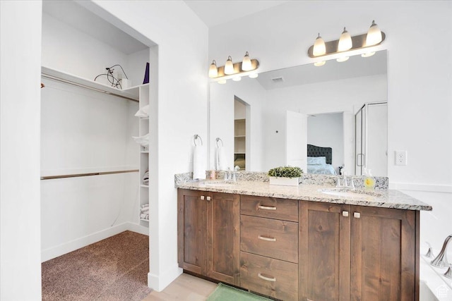 ensuite bathroom with a sink, a walk in closet, ensuite bath, and double vanity