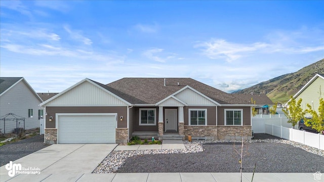 view of front of house featuring fence, a shingled roof, an attached garage, stone siding, and driveway