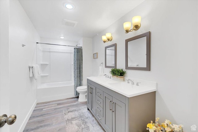 bathroom with double vanity, wood finished floors, shower / tub combo, a sink, and toilet