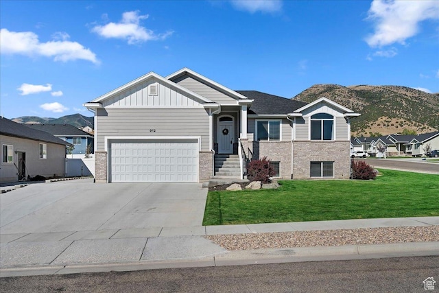 view of front of house with a mountain view, brick siding, driveway, a front lawn, and board and batten siding