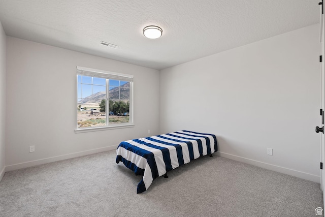carpeted bedroom featuring visible vents, a textured ceiling, and baseboards