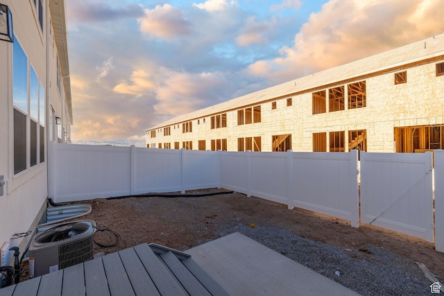 yard at dusk featuring central AC and a fenced backyard