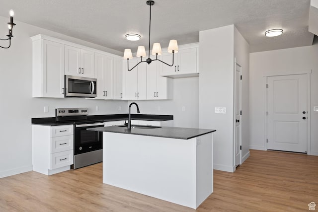 kitchen with white cabinets, dark countertops, an inviting chandelier, stainless steel appliances, and a sink