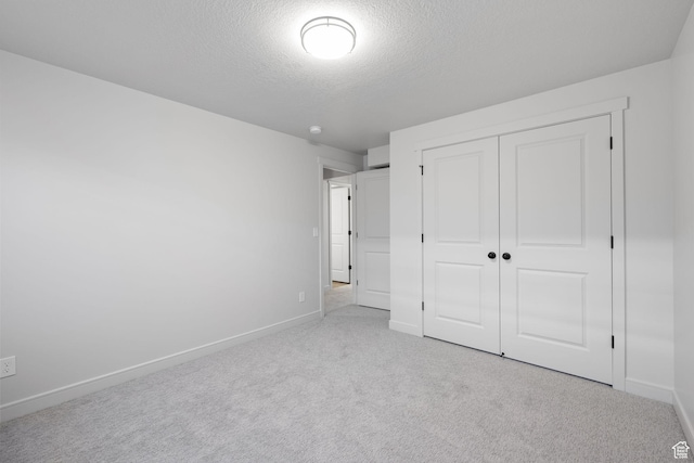 unfurnished bedroom with carpet, a textured ceiling, baseboards, and a closet