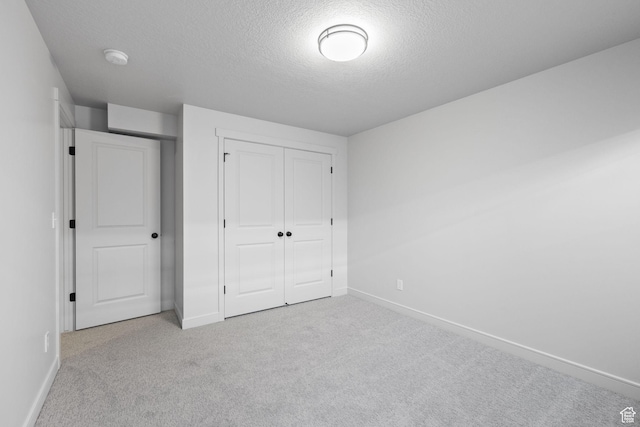 unfurnished bedroom featuring carpet floors, a textured ceiling, baseboards, and a closet
