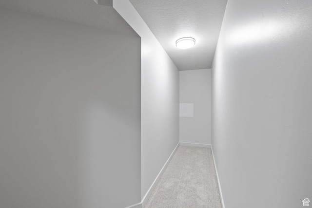 hallway featuring a textured ceiling, carpet floors, and baseboards
