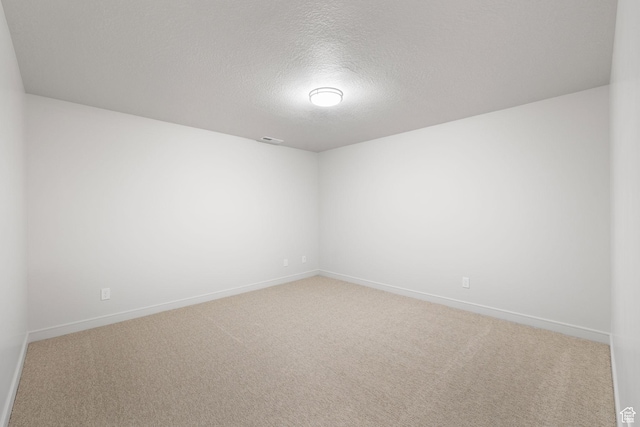 carpeted spare room featuring a textured ceiling, visible vents, and baseboards