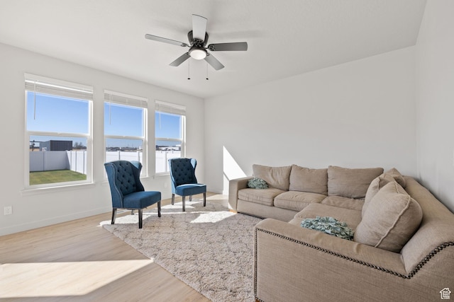living room featuring ceiling fan, baseboards, and wood finished floors