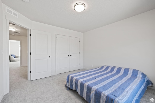 bedroom featuring a textured ceiling, carpet floors, a closet, and visible vents