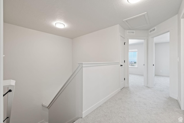 hall featuring visible vents, light carpet, an upstairs landing, and attic access
