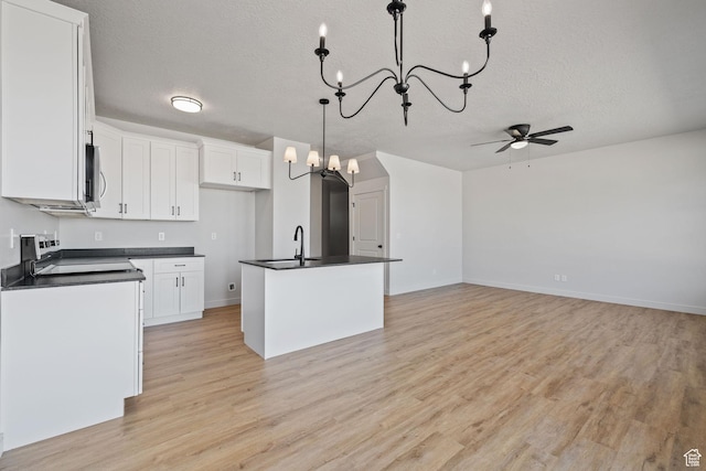 kitchen with light wood-style flooring, dark countertops, range, and white cabinets