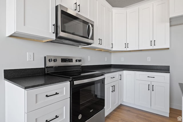 kitchen with stainless steel appliances, dark countertops, and white cabinets